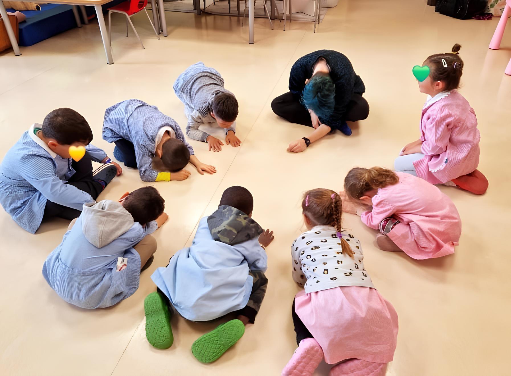 Several children are sitting in a circle on the floor during a music workshop