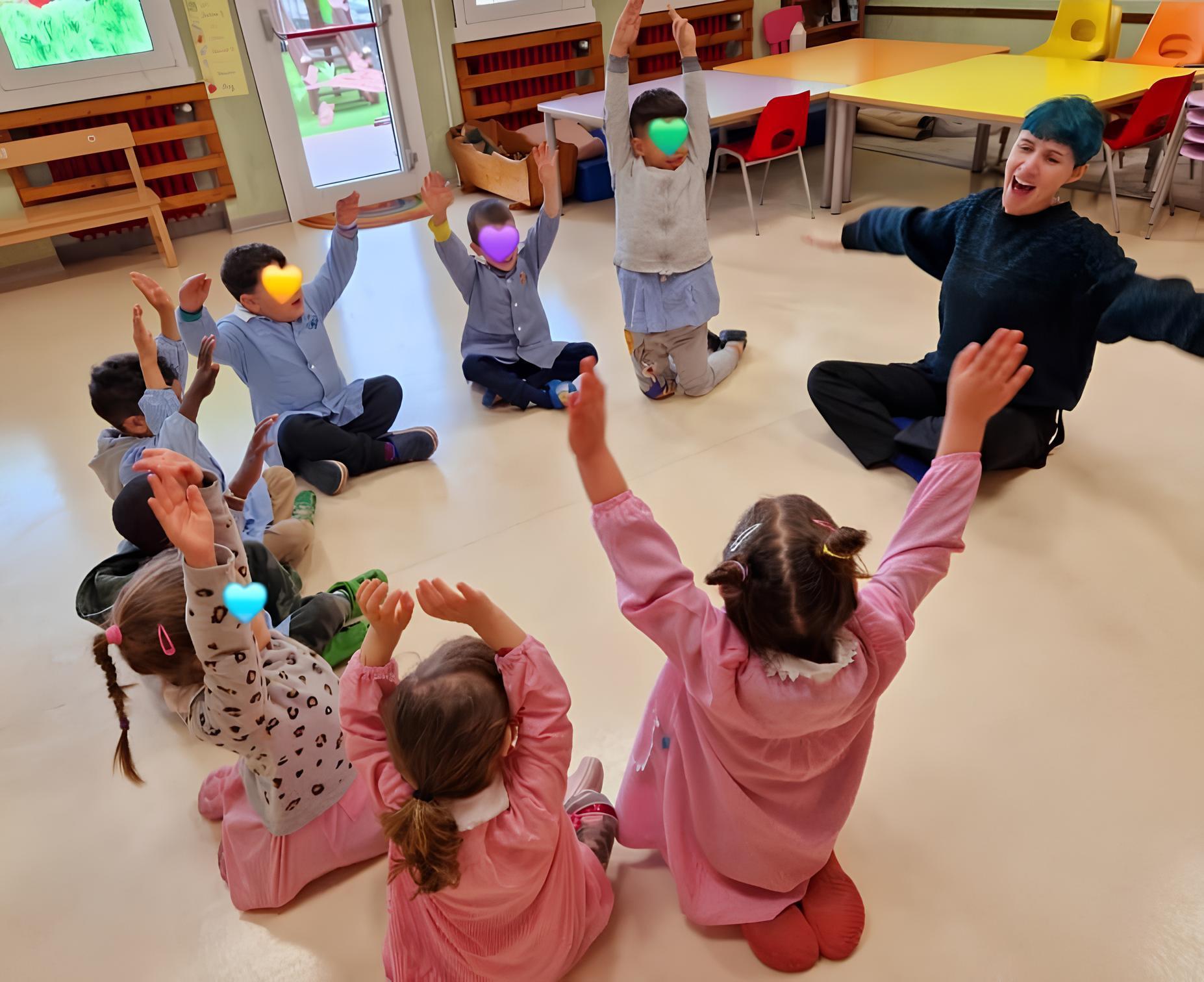 A group of children is singing indoors. They are in a kindergarten setting, engaged in vocal activities on the floor. The image features both boys and girls.